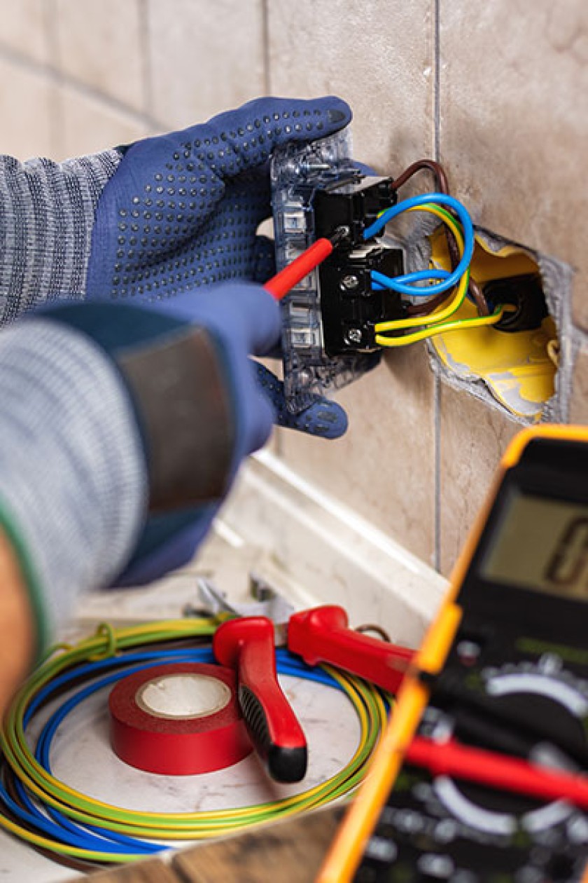 An individual performing electrical work to an outlet.